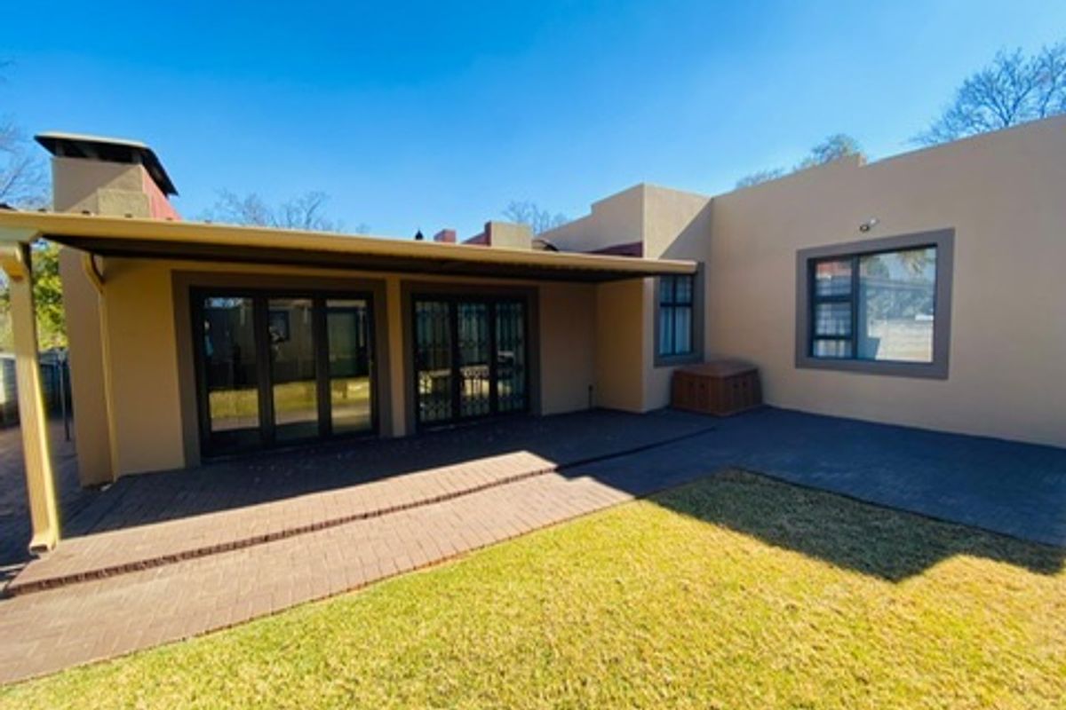 Rear view of the property featuring a covered patio area with brick paving, sliding glass doors, and an external fireplace chimney.