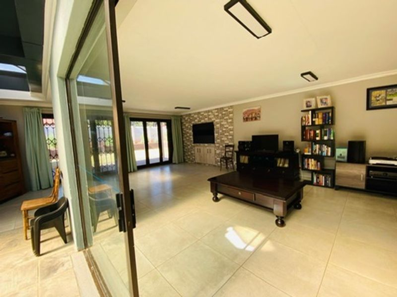 Spacious living room featuring large sliding glass doors, tiled flooring, and a stone feature wall, offering a bright and open living environment.