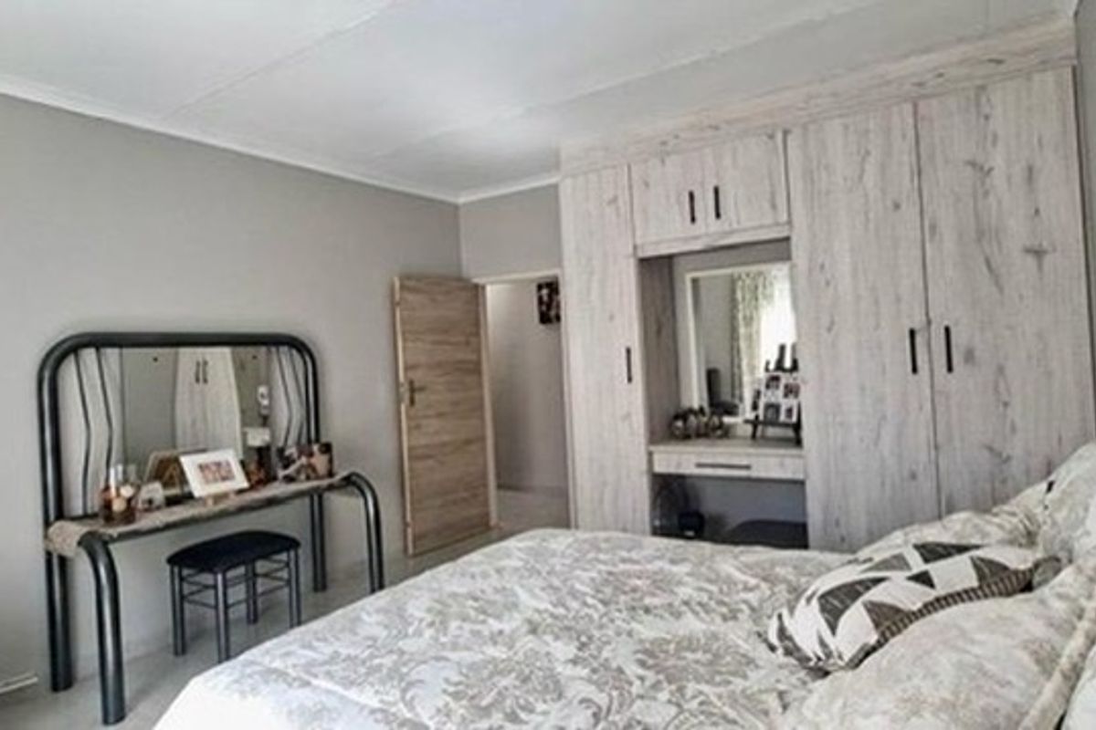 A well-maintained bedroom featuring neutral wall tones and extensive built-in cabinetry including a integrated vanity unit.