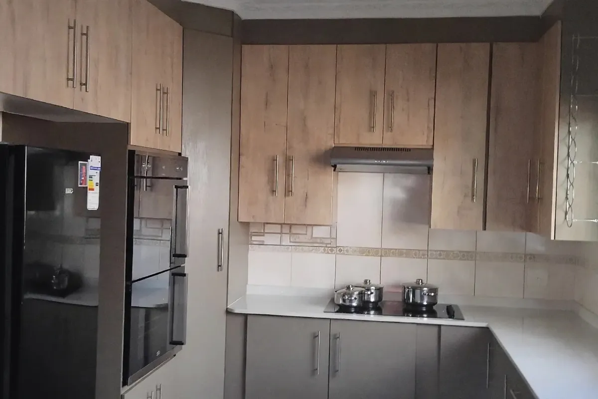 A functional kitchen featuring modern wood-look cabinetry, built-in oven, hob with extractor fan, and ample counter space.