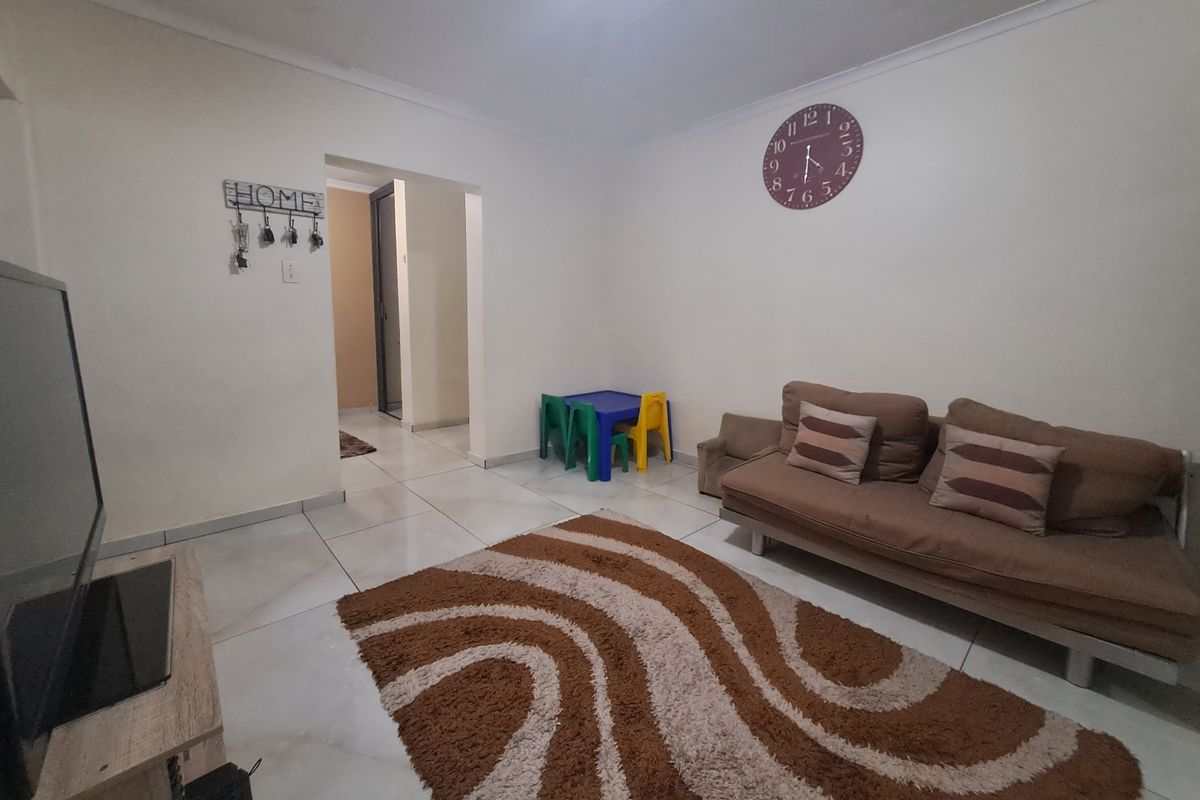 A living room featuring neutral tiled flooring and clean white walls, providing a functional and well-lit space for relaxation.