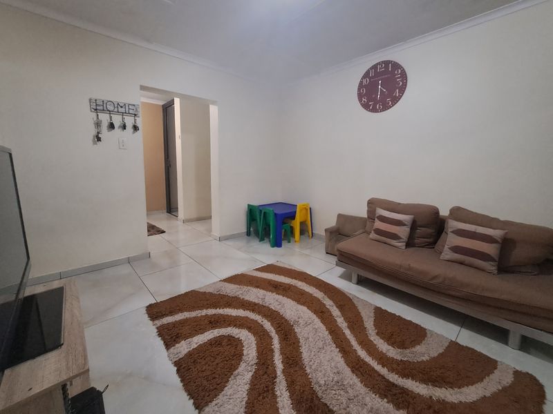 A living room featuring neutral tiled flooring and clean white walls, providing a functional and well-lit space for relaxation.