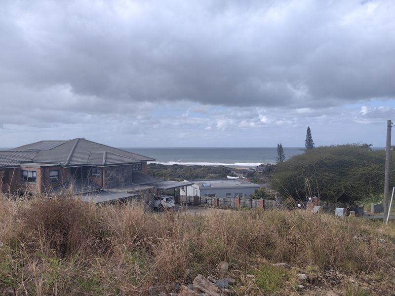 A scenic view overlooking the coastline and ocean from an elevated vacant residential plot.