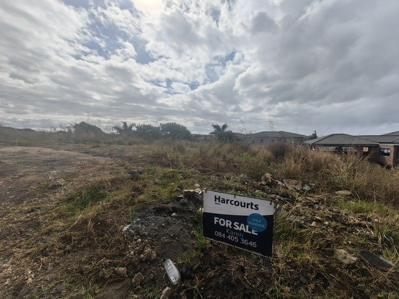 A vacant residential plot of land featuring natural vegetation and a for sale sign, offering potential for future development.
