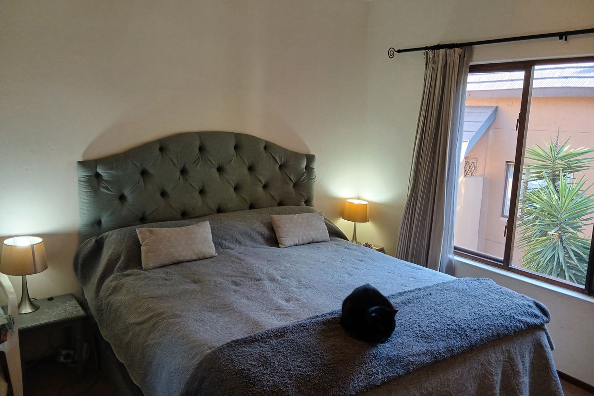 A cozy bedroom featuring a large window with natural light, neutral wall finishes, and a functional layout.
