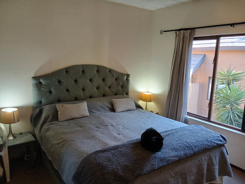 A cozy bedroom featuring a large window with natural light, neutral wall finishes, and a functional layout.