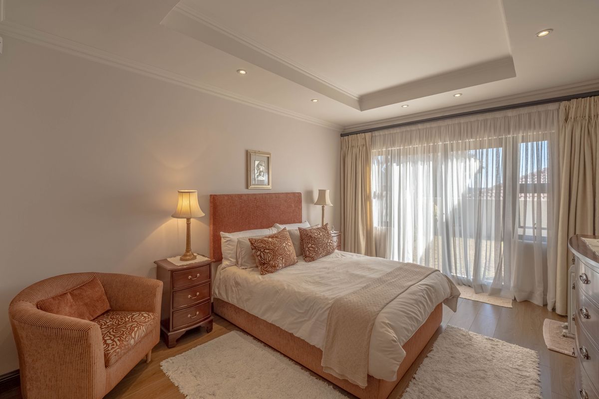 A well-maintained bedroom featuring a tray ceiling with recessed lighting, laminate flooring, and a large sliding glass door providing access to the exterior.