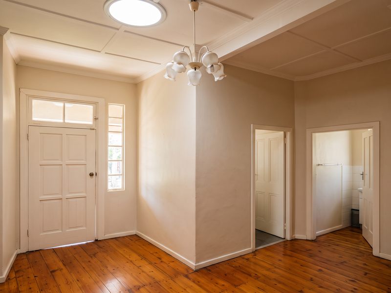 A bright and spacious entrance hall featuring polished timber flooring, a classic panelled front door, and a skylight, providing a welcoming transition area.