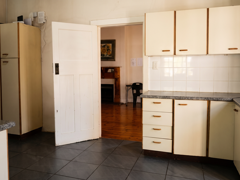 A functional kitchen space featuring built-in cabinetry, laminate countertops, and tiled flooring, offering a blank canvas for potential modern updates.