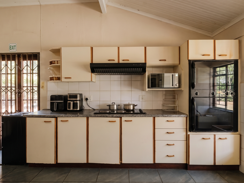 A functional kitchen featuring built-in cabinetry, an electric hob, extractor fan, and integrated oven, with direct access to an exterior security gate.