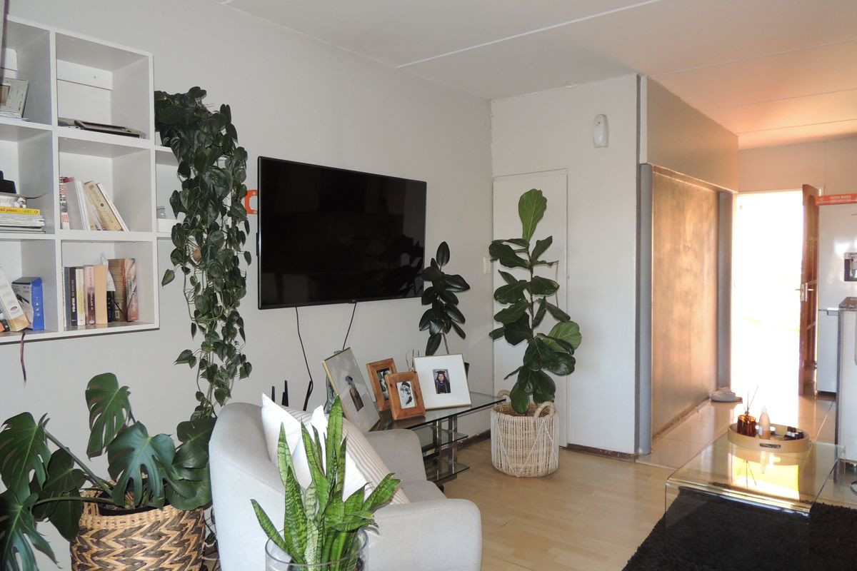 A living room featuring light laminate flooring and built-in wall shelving, providing a functional and bright space for relaxation.