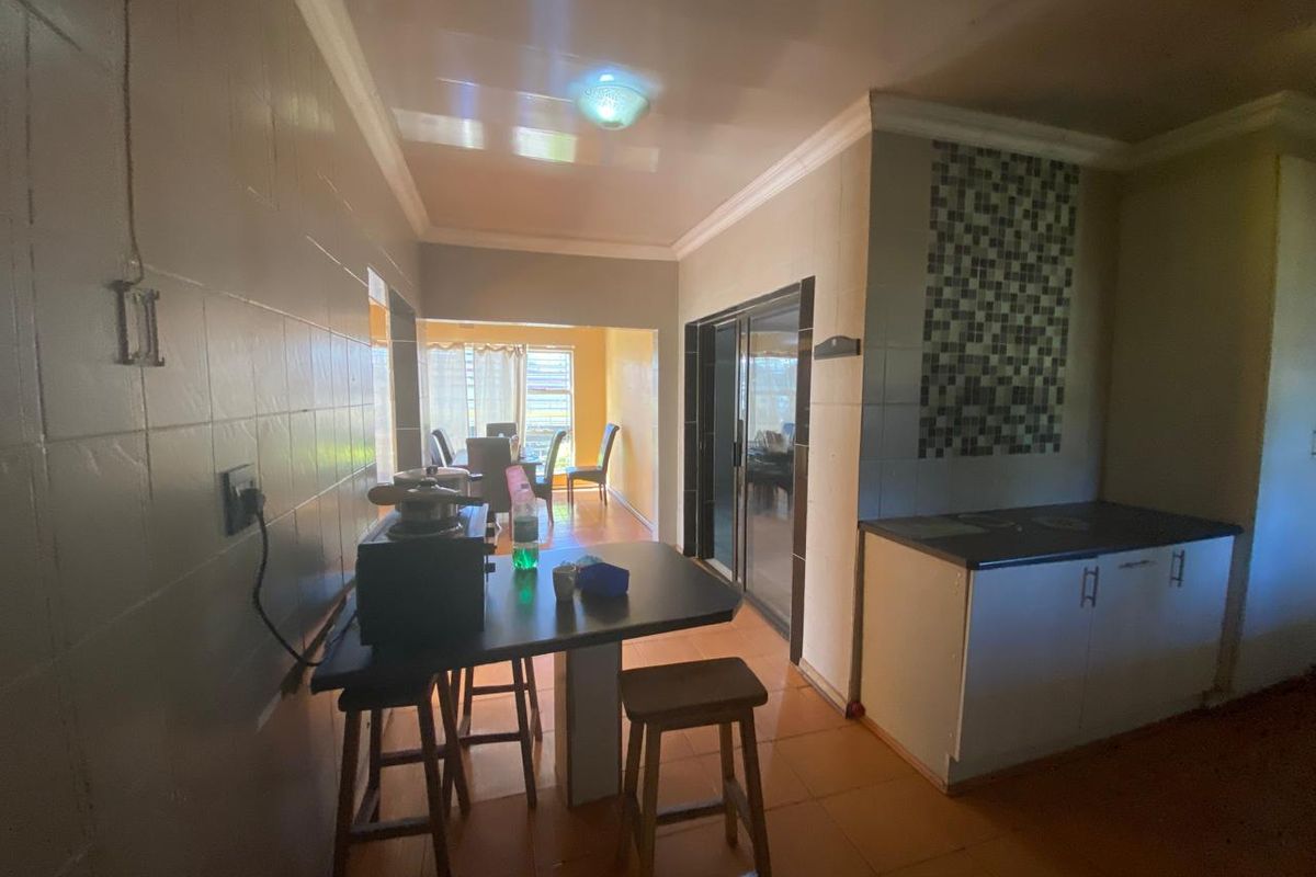 A functional kitchen area featuring tiled walls, built-in cabinetry with laminate countertops, and sliding glass doors leading to an adjacent dining space.