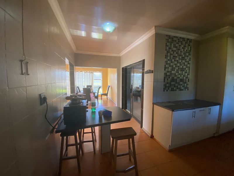 A functional kitchen area featuring tiled walls, built-in cabinetry with laminate countertops, and sliding glass doors leading to an adjacent dining space.