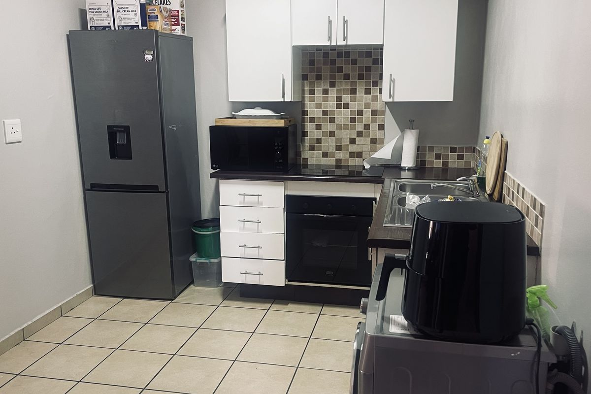 Compact kitchen featuring white cabinetry, mosaic tile backsplash, built-in oven, and tiled flooring, providing a functional workspace.