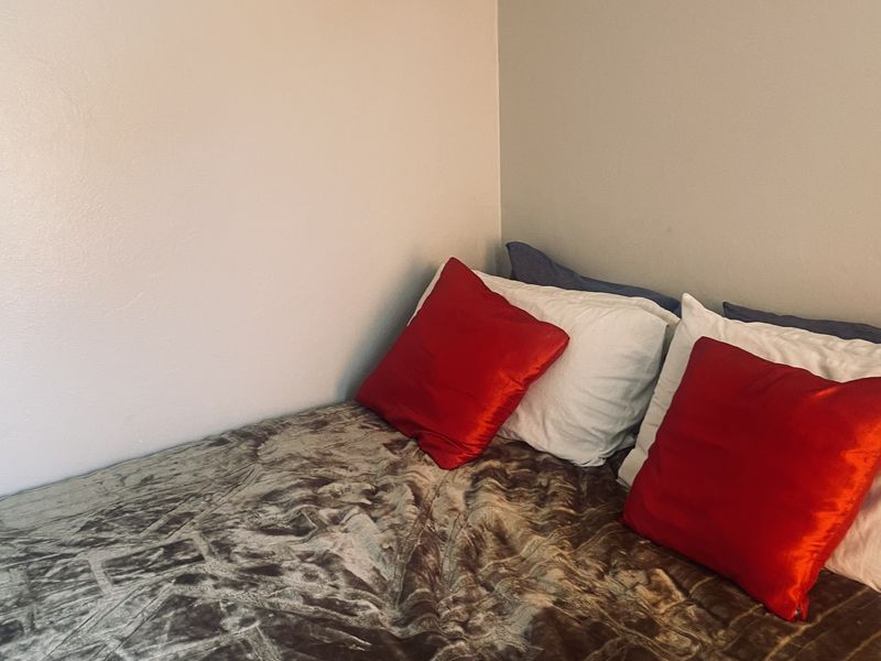 A corner view of a bedroom featuring plain walls and neutral finishes.