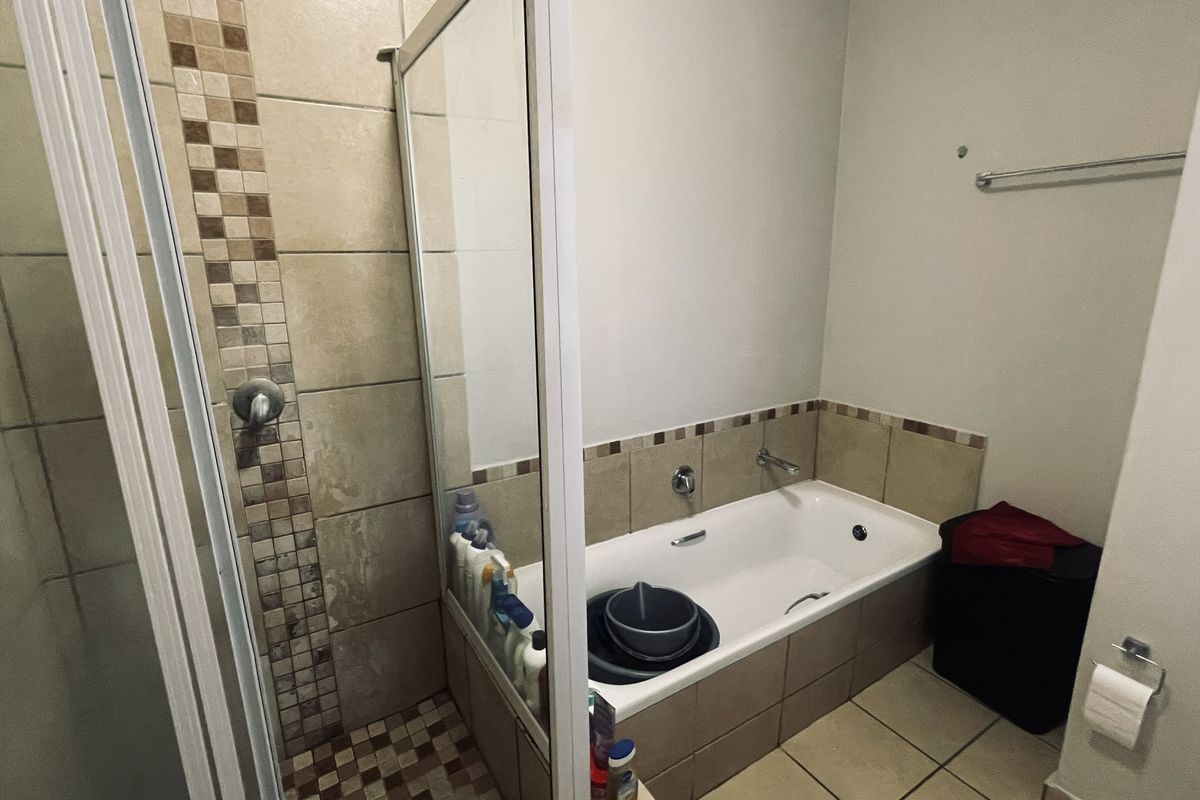 A functional bathroom featuring a separate shower enclosure and a bathtub with tiled splashbacks and neutral floor tiling.