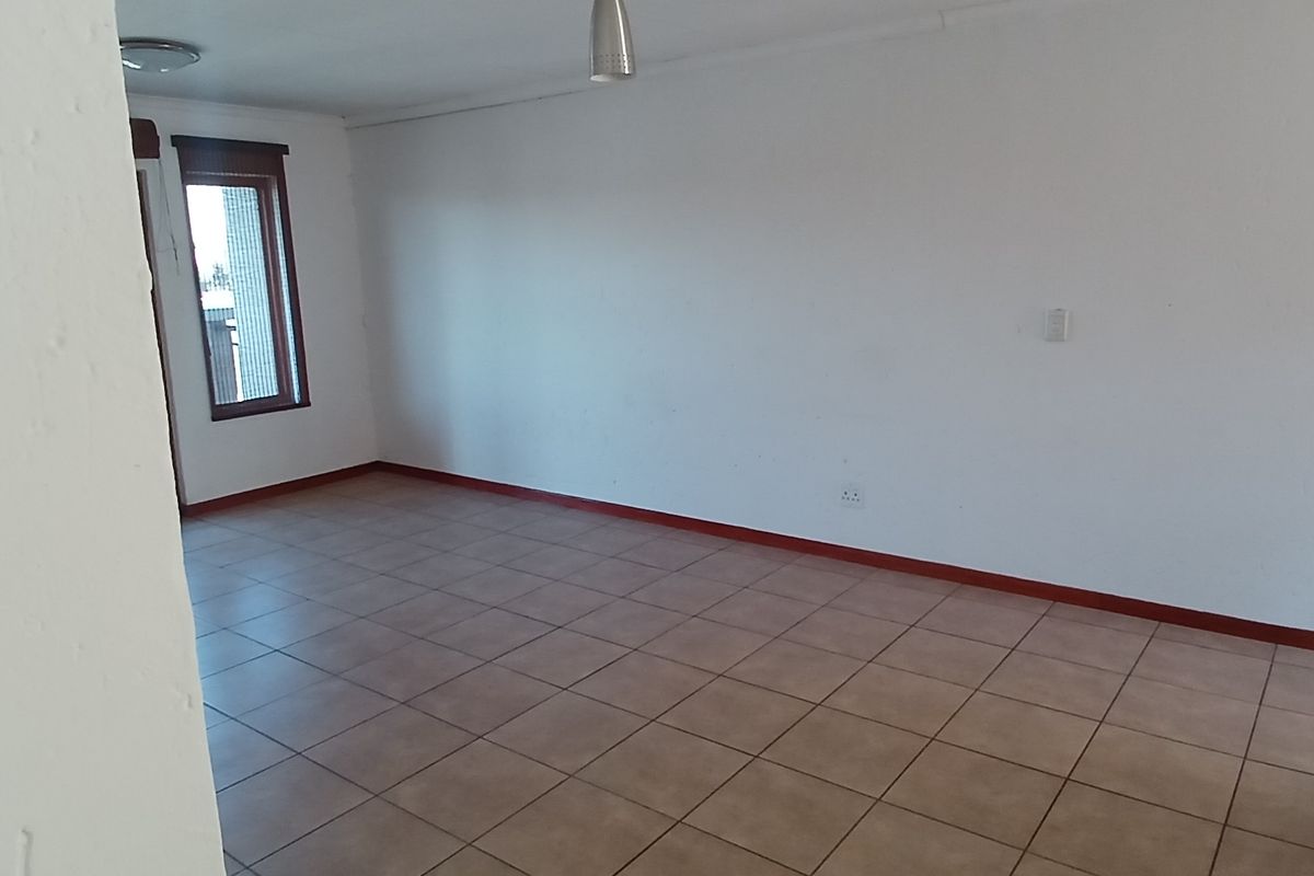 An empty, open-plan living area featuring neutral tiled flooring and white walls, providing a blank canvas for interior design.