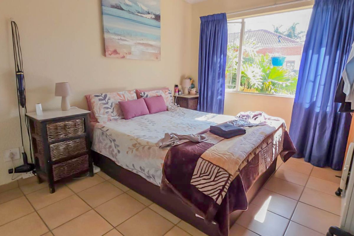A functional bedroom featuring tiled flooring and a large window that allows for natural light.