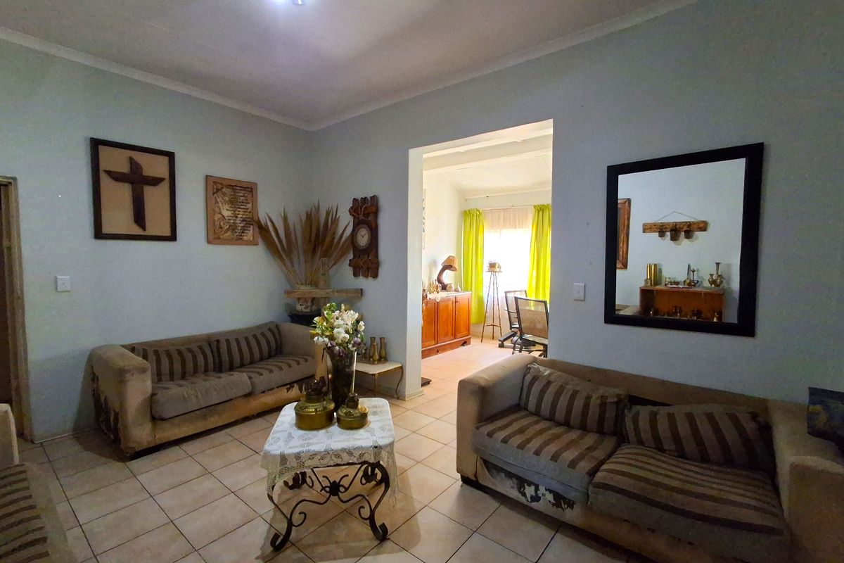 A living room featuring ceramic floor tiles and a coved ceiling, with an open transition to an adjacent room.