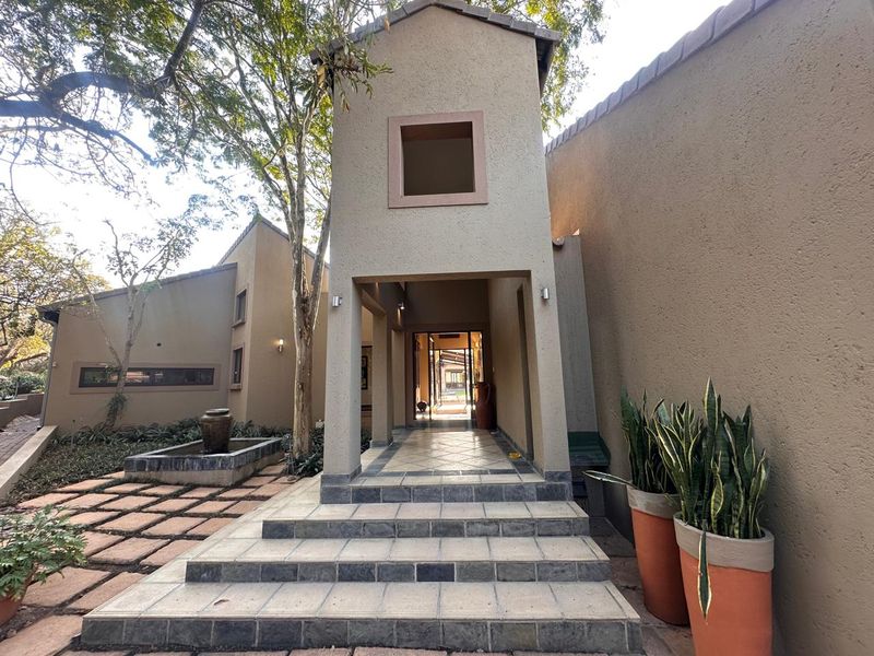 A welcoming front entrance featuring a covered walkway, tiled steps, and a decorative water feature set against a stucco facade.