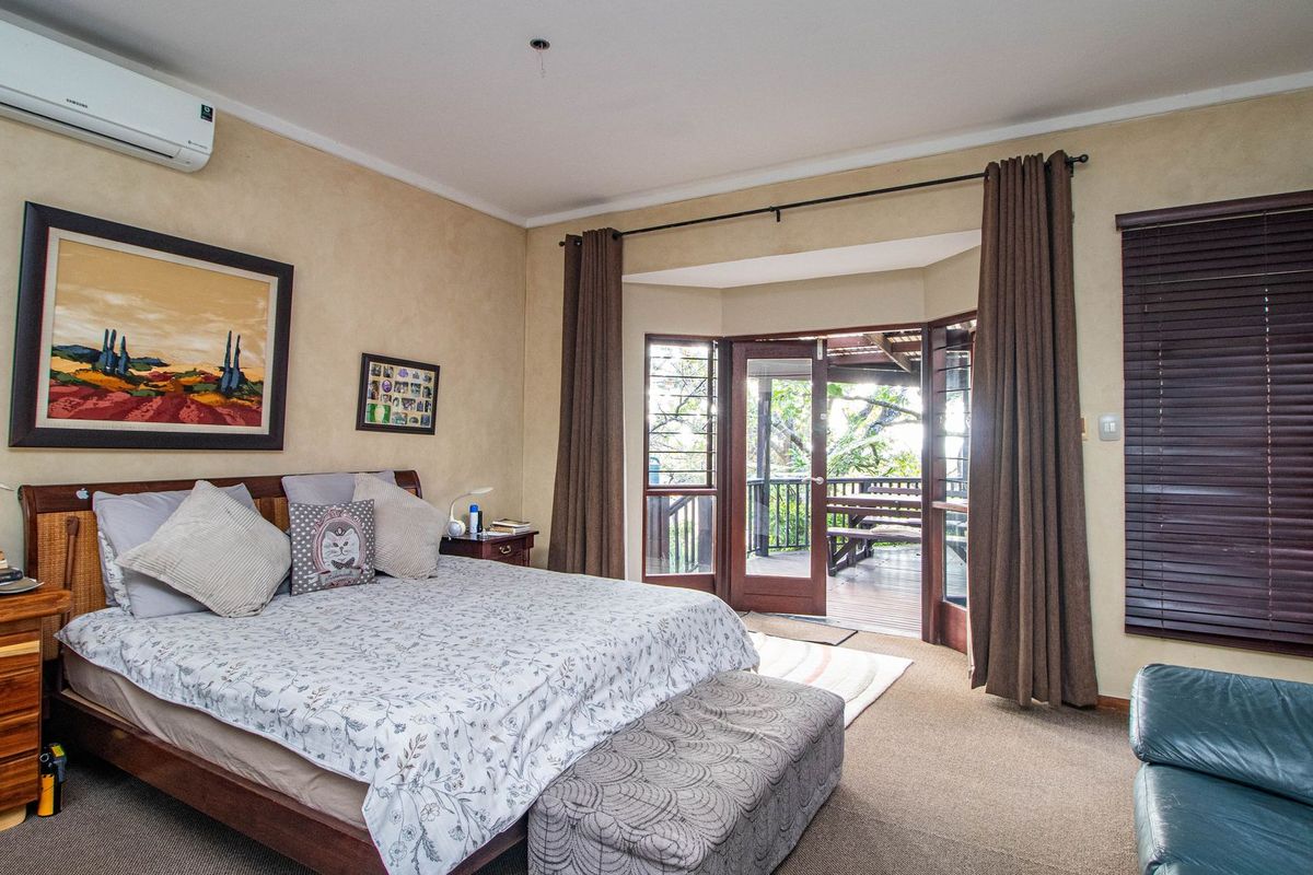 Spacious bedroom featuring carpet flooring, a split-system air conditioner, and direct access to an outdoor deck through large bay-style french doors.