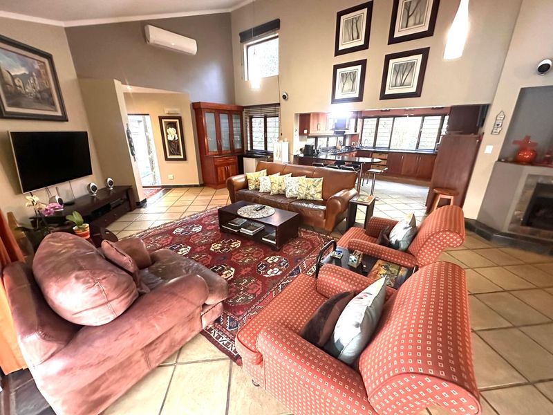 Spacious open-plan living area featuring vaulted ceilings, tiled flooring, a fireplace, and an integrated kitchen with built-in cabinetry.