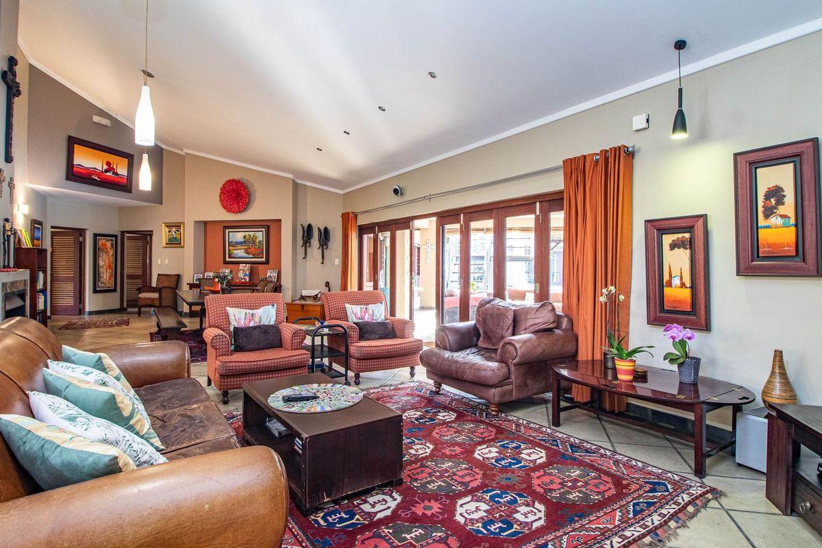 Spacious living room featuring a vaulted ceiling, tiled flooring, and large timber-framed sliding doors that provide seamless access to the outdoor area.