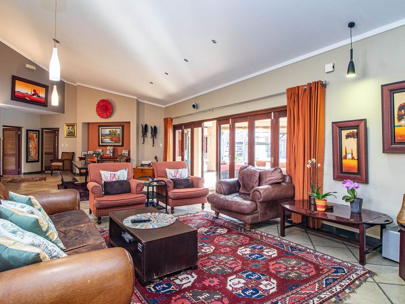Spacious living room featuring a vaulted ceiling, tiled flooring, and large timber-framed sliding doors that provide seamless access to the outdoor area.