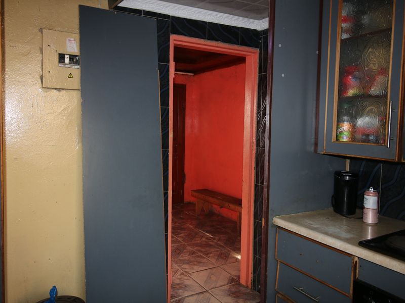 A dated kitchen area featuring built-in cabinetry and tiled flooring, showing significant signs of wear and requiring cosmetic updates.