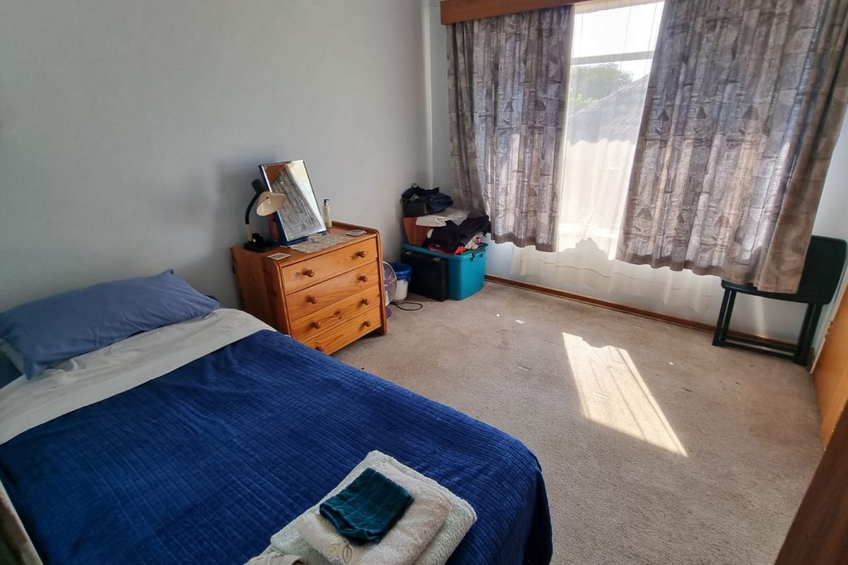A functional bedroom featuring carpeted flooring and large windows with curtain tracks, offering a blank canvas for potential interior updates.