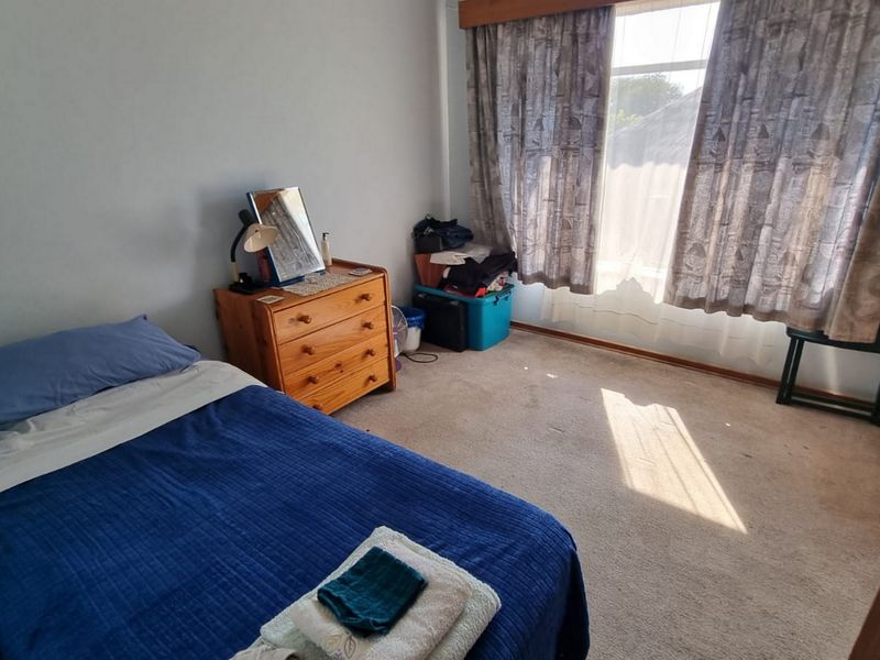 A functional bedroom featuring carpeted flooring and large windows with curtain tracks, offering a blank canvas for potential interior updates.