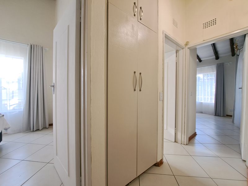 A bright hallway featuring tiled flooring and built-in storage cupboards, providing access to multiple rooms within the townhouse.