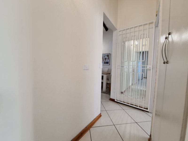 A bright hallway featuring tiled flooring and a white security gate leading into the main living area.