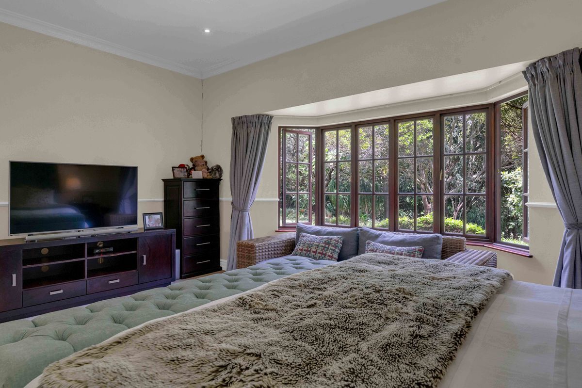Spacious bedroom featuring a large bay window with garden views, crown molding, and recessed lighting.