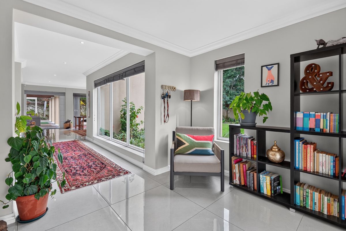 Bright living area featuring large aluminium windows, polished porcelain floor tiles, and recessed downlighting, creating a seamless flow to the outdoor patio area.