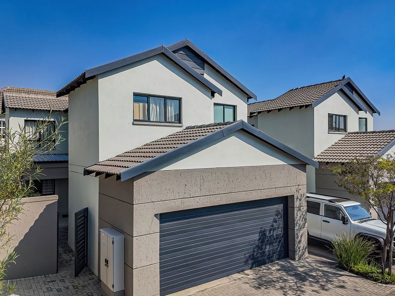 Modern townhouse exterior featuring a tiled roof, paved driveway, and a secure garage, showcasing a well-maintained contemporary facade.