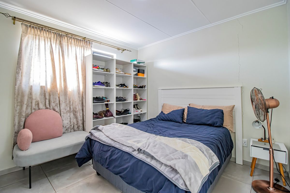A bedroom featuring tiled flooring and a visible vertical wall crack, offering a functional space ready for cosmetic updates.