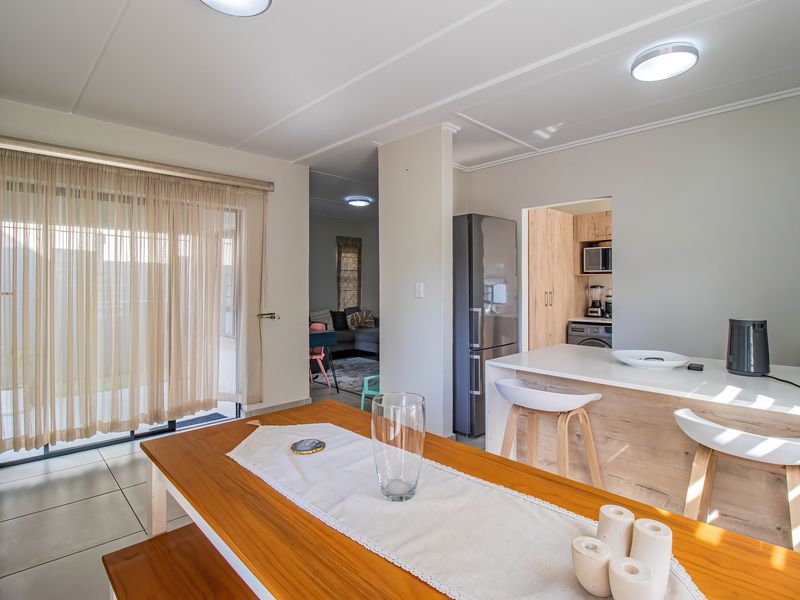 Open plan living and dining area featuring a modern kitchen island, tiled flooring, and sliding glass doors leading to the outdoor space.
