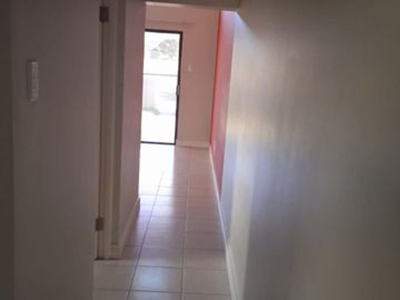 A functional hallway featuring tiled flooring and a sliding glass door leading to an outdoor area, providing a clean transition between living spaces.
