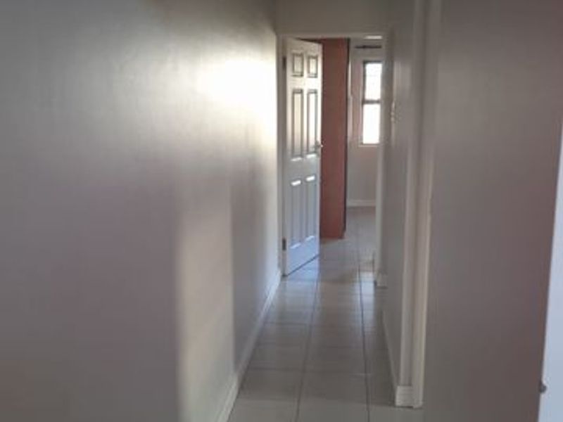 A simple, tiled hallway connecting multiple rooms within the apartment, featuring neutral wall tones and standard internal door access.
