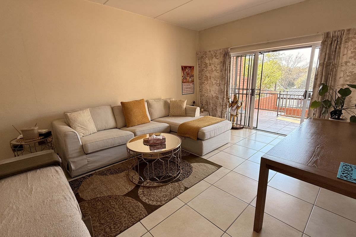 A bright living room featuring tiled flooring and large sliding glass doors that provide direct access to an outdoor balcony area.