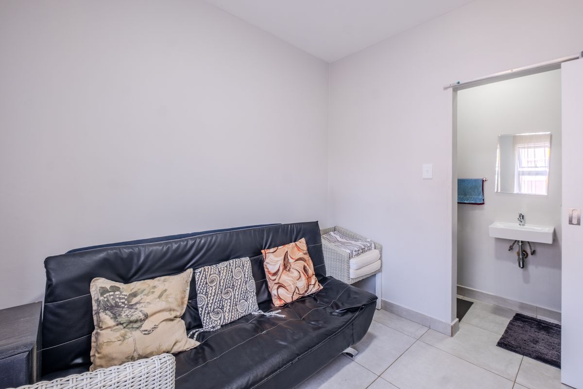 A bedroom featuring tiled flooring and an en-suite bathroom area with a wall-mounted basin and chrome fixtures.