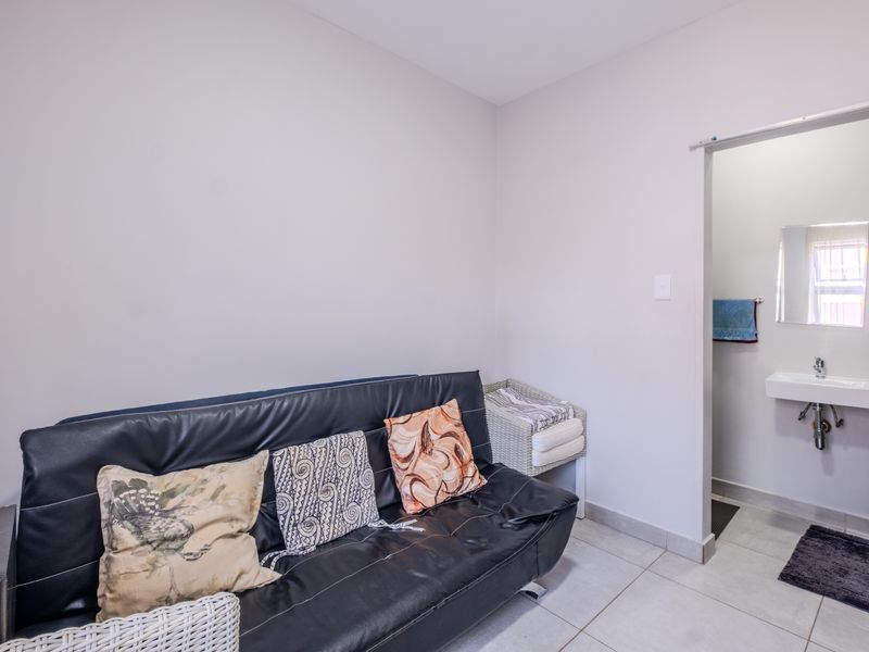 A bedroom featuring tiled flooring and an en-suite bathroom area with a wall-mounted basin and chrome fixtures.
