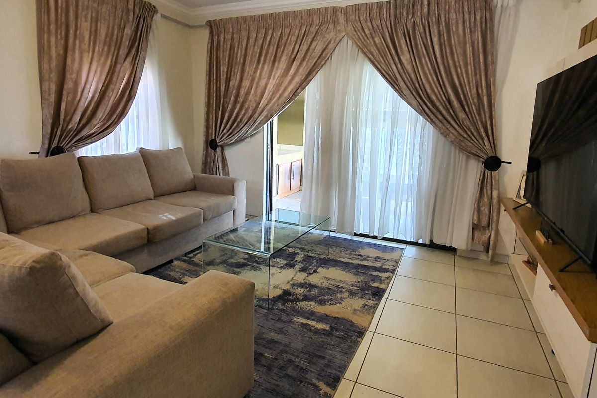 A comfortable living room featuring tiled flooring and a large sliding glass door that provides access to the outdoor area.