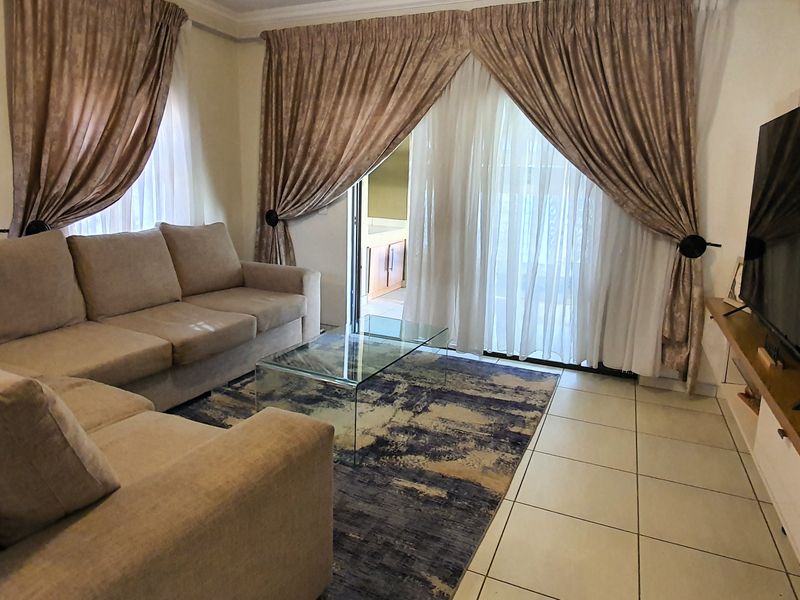 A comfortable living room featuring tiled flooring and a large sliding glass door that provides access to the outdoor area.
