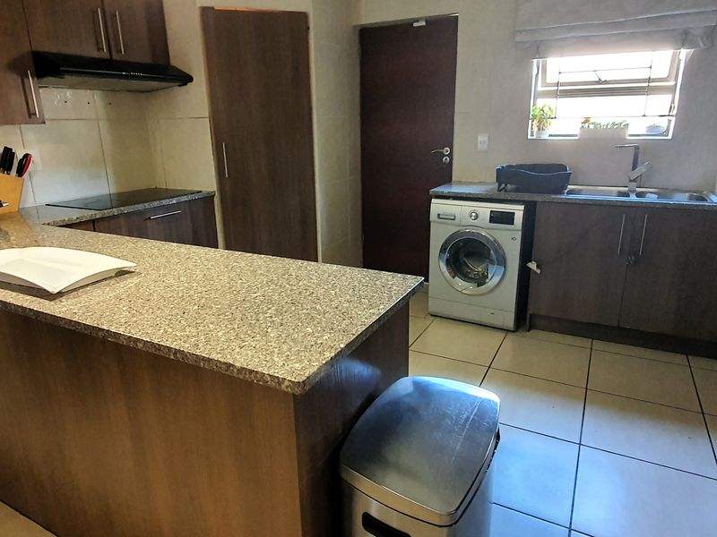 A functional kitchen featuring dark wood cabinetry, granite countertops, tiled flooring, and integrated appliances, offering a practical layout for daily use.