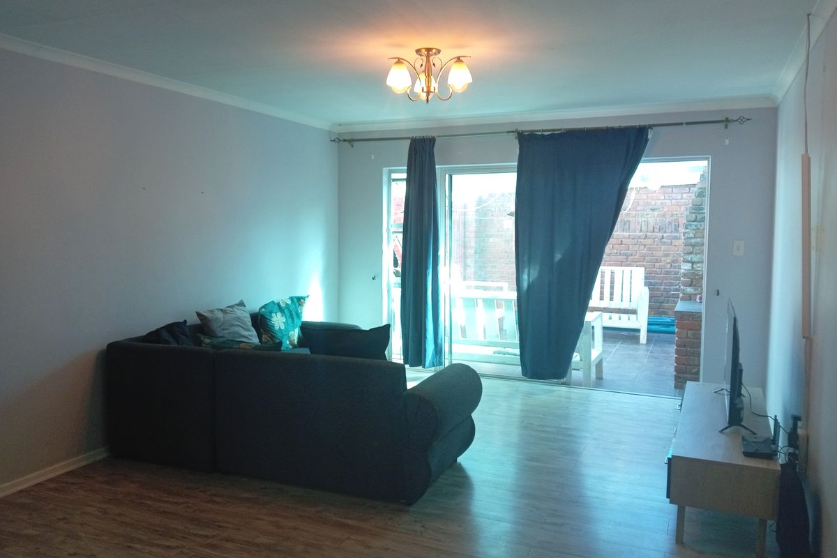 A living room featuring laminate flooring and a sliding glass door providing access to an outdoor patio area.