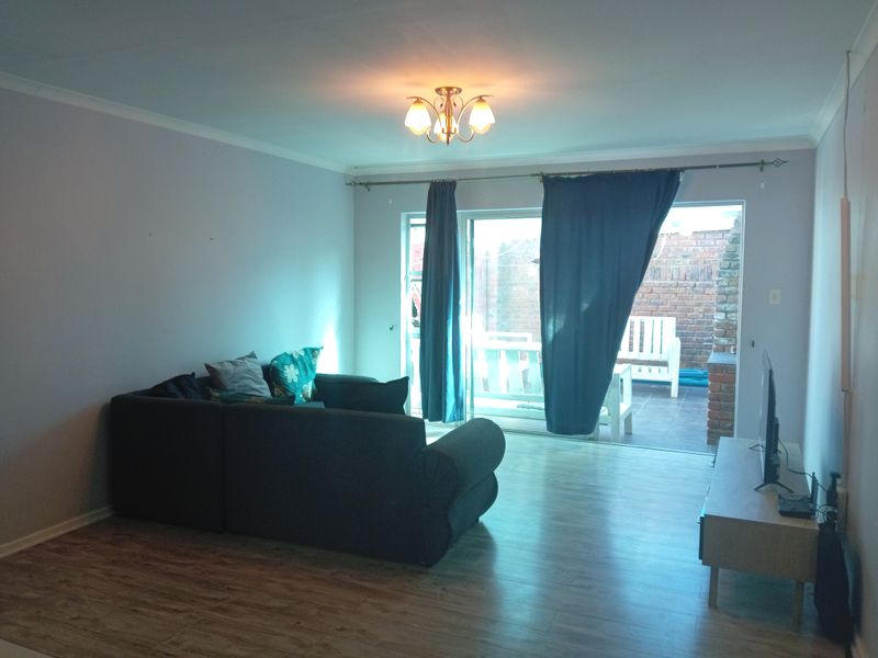 A living room featuring laminate flooring and a sliding glass door providing access to an outdoor patio area.