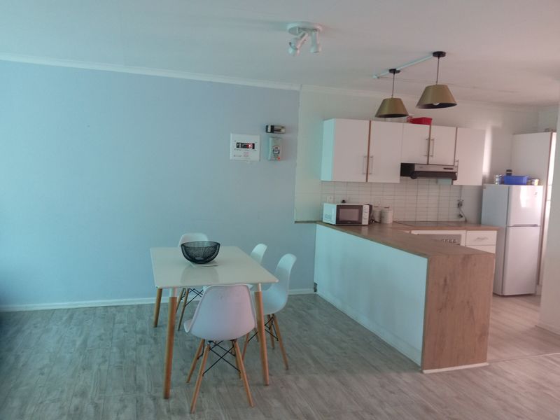 Open-plan living and dining area featuring a functional kitchen with laminate countertops, built-in cabinetry, and a tiled backsplash.