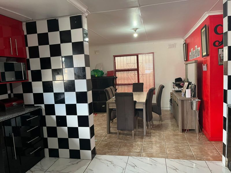 Open plan kitchen and dining area featuring high-contrast checkered tiling and bold red accent walls, offering a distinct retro-inspired aesthetic.